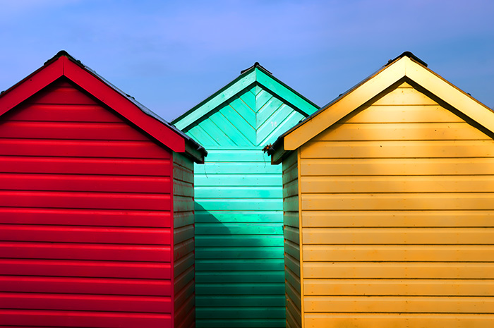 Three colourful sheds alongside and overlapping against a blue sky