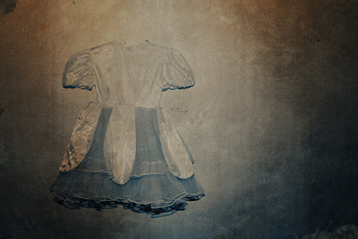 Dreamlike, faded image of a girls dress against a decaying wall