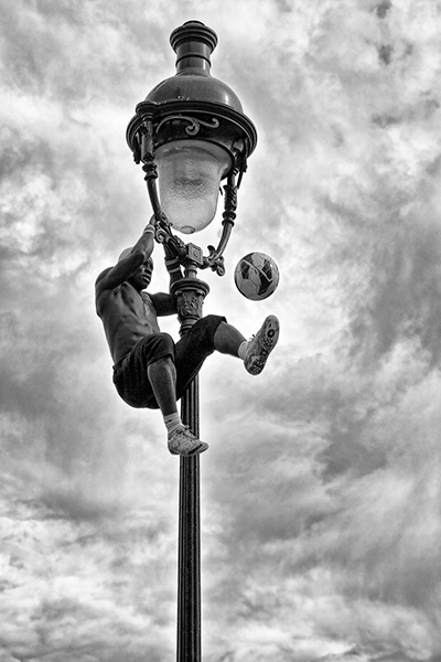 Iya Traoré, football freestyler, demonstrates his skills while hanging from a lamp post in Paris