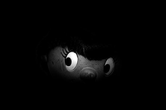 Partly lit Noddy face with eyes looking sideways surrounded by blackness