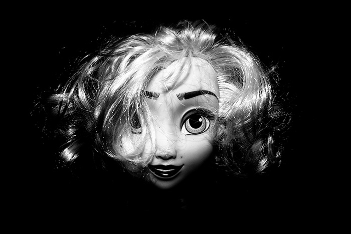 Portrait of a glamorous looking doll's face surrounded by blackness