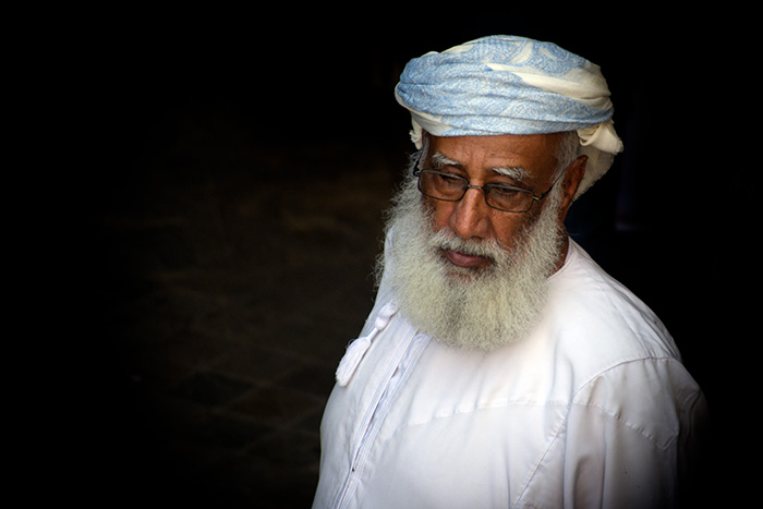 Portrait of Omani man in traditional clothing taken from an elevated angle against a dark background