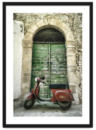 A dilapidated vintage motor scooter is parked in front of a weathered wooden door in a backstreet in Tunisia