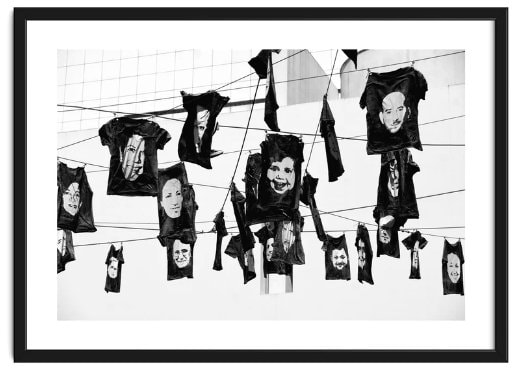 T-shirts with faces with various expressions hang from wires above