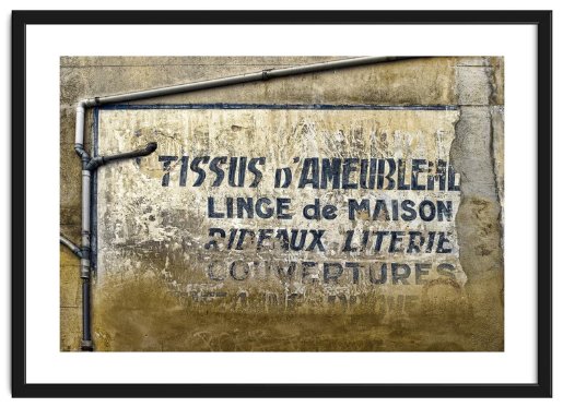 A fading wall with French writing and prominent drainpipes