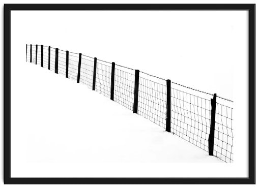 High contrast black and white image of a wire fence sitting in snow