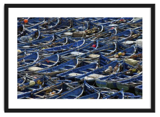 Framed image of identical blue fishing dinghies packed tightly together sit in the harbour at Eassouira, Morocco