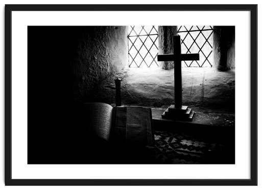 Framed image of a cross and open Bible dimly lit by available light in an ancient church