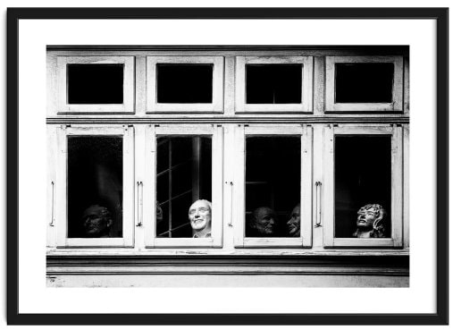 Wooden framed window with sculptured heads sitting inside