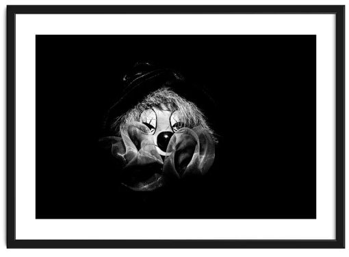 Framed portrait of a puppet clown with face partially obscured by clothing, surrounded by blackness