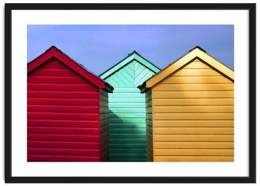 Framed image of three colourful sheds alongside and overlapping against a blue sky